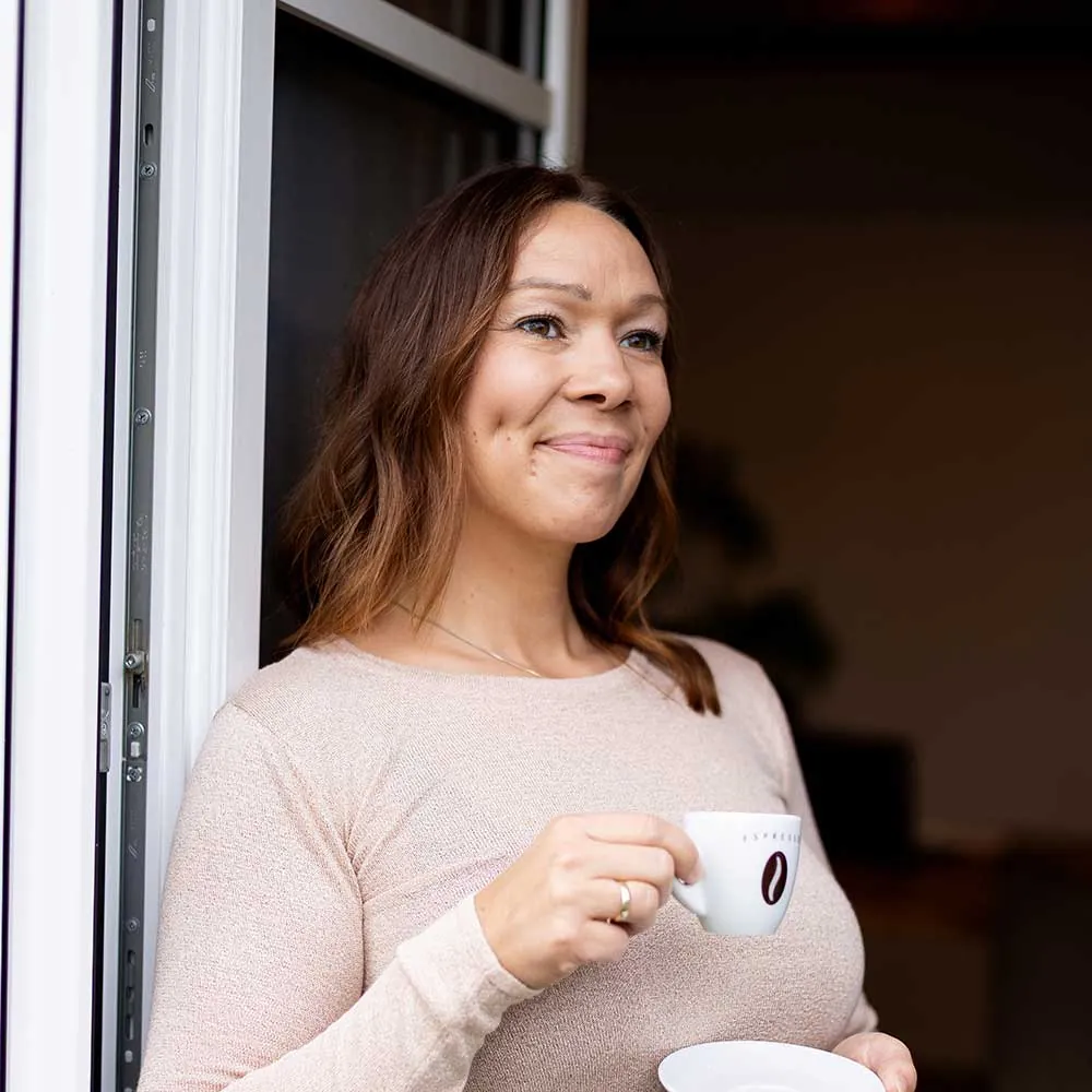 Sabine Dück steht am Fenster mit einer Kaffeetasse – Feel-Good-Woman-Programm für Mütter bei Einfach Gesund Leben